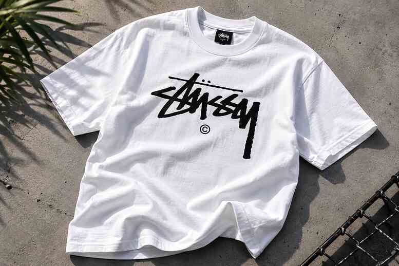 Stussy T Shirt flat lay on white surface showing classic stock logo graphic